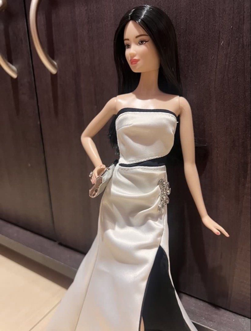 PTMI Barbie gown (Category: Evening dresses & gowns) located in Rizal. Submitted by arryn (Listing ID 1454550645, Image 3). Description: - Elegant black and white strapless evening gown for Barbie dolls. - Features a daring high slit for a glamorous look. - Adorned with a beautiful jeweled accent on the side. - Includes a stylish small silver clutch purse. - Ideal for Barbie collectors and imaginative play scenarios. Pm for details.
