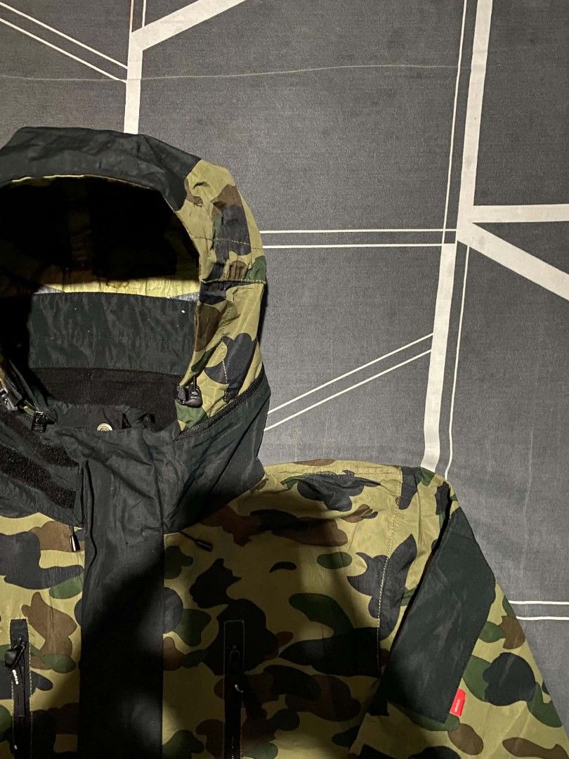 WTAPS/BAPE Camo Hooded Jacket Size X03 (Category: Coats, Jackets and Outerwear) located in Manila. Submitted by raymondrob54698 (Listing ID 1454426560, Image 2). Description: - Authentic WTAPS x BAPE collaboration jacket - Features iconic BAPE camouflage pattern - Stylish black accents on sleeves and hood - Multiple functional zip pockets on the front - Adjustable drawstring hem for a customized fit - Tag reads 'ISSUE, WTAPS/BAPE' - Size X03 87 2