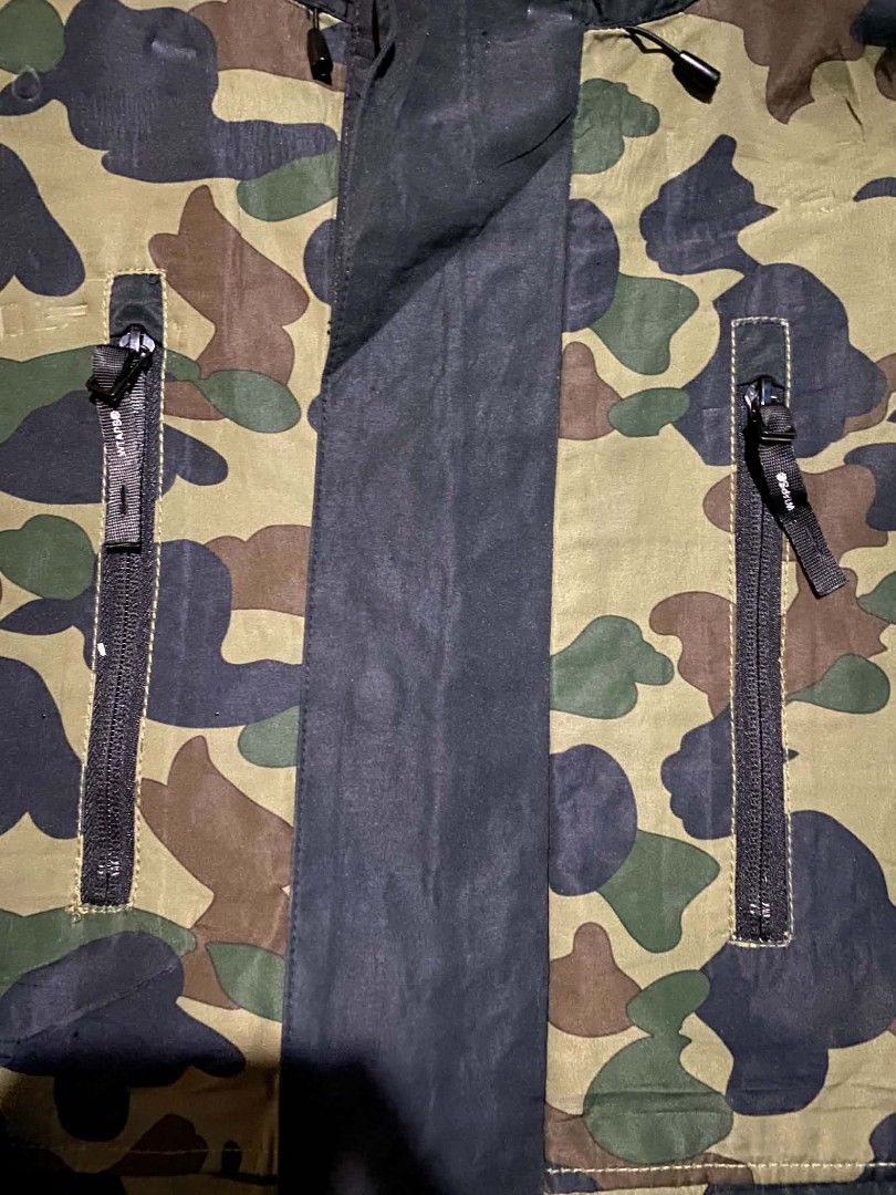 WTAPS/BAPE Camo Hooded Jacket Size X03 (Category: Coats, Jackets and Outerwear) located in Manila. Submitted by raymondrob54698 (Listing ID 1454426560, Image 3). Description: - Authentic WTAPS x BAPE collaboration jacket - Features iconic BAPE camouflage pattern - Stylish black accents on sleeves and hood - Multiple functional zip pockets on the front - Adjustable drawstring hem for a customized fit - Tag reads 'ISSUE, WTAPS/BAPE' - Size X03 87 2