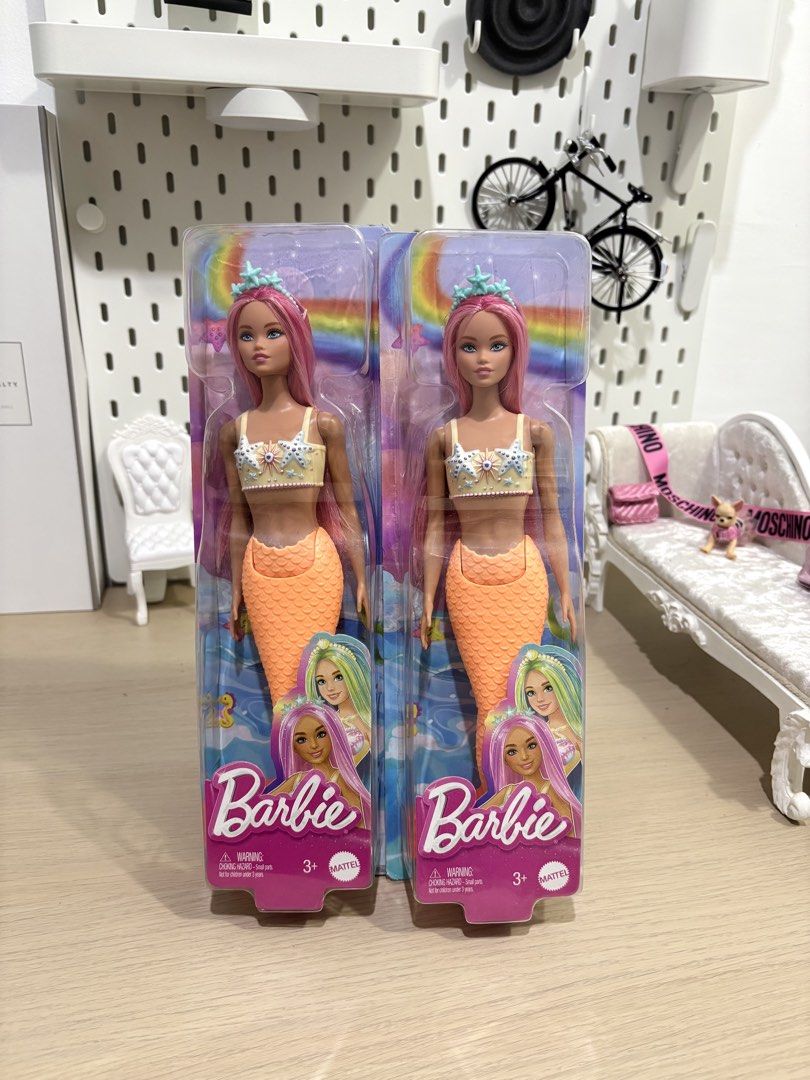 Barbie Mermaid Doll (2 pcs) (Category: Kids Toys) located in Rodriguez. Submitted by michaelstyles (Listing ID 1454748331, Image 2). Description: For only 800php each! 😍 - Set of 2 Barbie mermaid dolls - Features vibrant pink hair - Adorable orange mermaid tails - Each doll wears a seashell bikini top - Topped with a sparkling starfish crown - Packaging boasts a fun rainbow and ocean theme - Ideal for Barbie collectors and imaginative playtime.