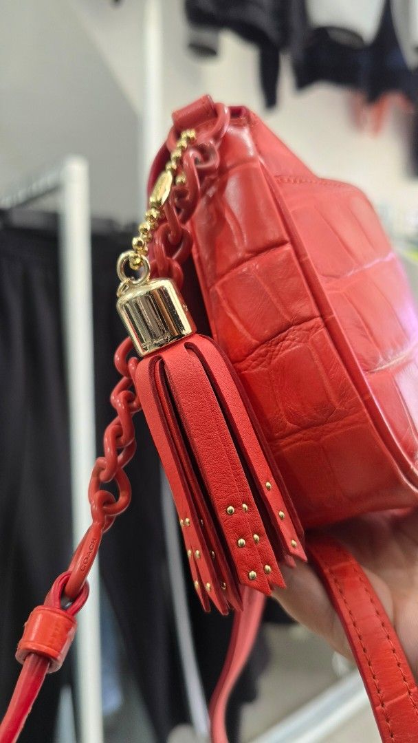 Coach Red Croc Embossed Leather Crossbody Bag (Category: Cross-body Bags) located in Manila. Submitted by nnthrift_ (Listing ID 1454680972, Image 3). Description: - Authentic Orange Coach bag - Luxurious croc embossed leather - Elegant gold hardware - Stylish tassel detail - Convenient chain strap - Interior Coach New York tag - Versatile for nights out or everyday wear.