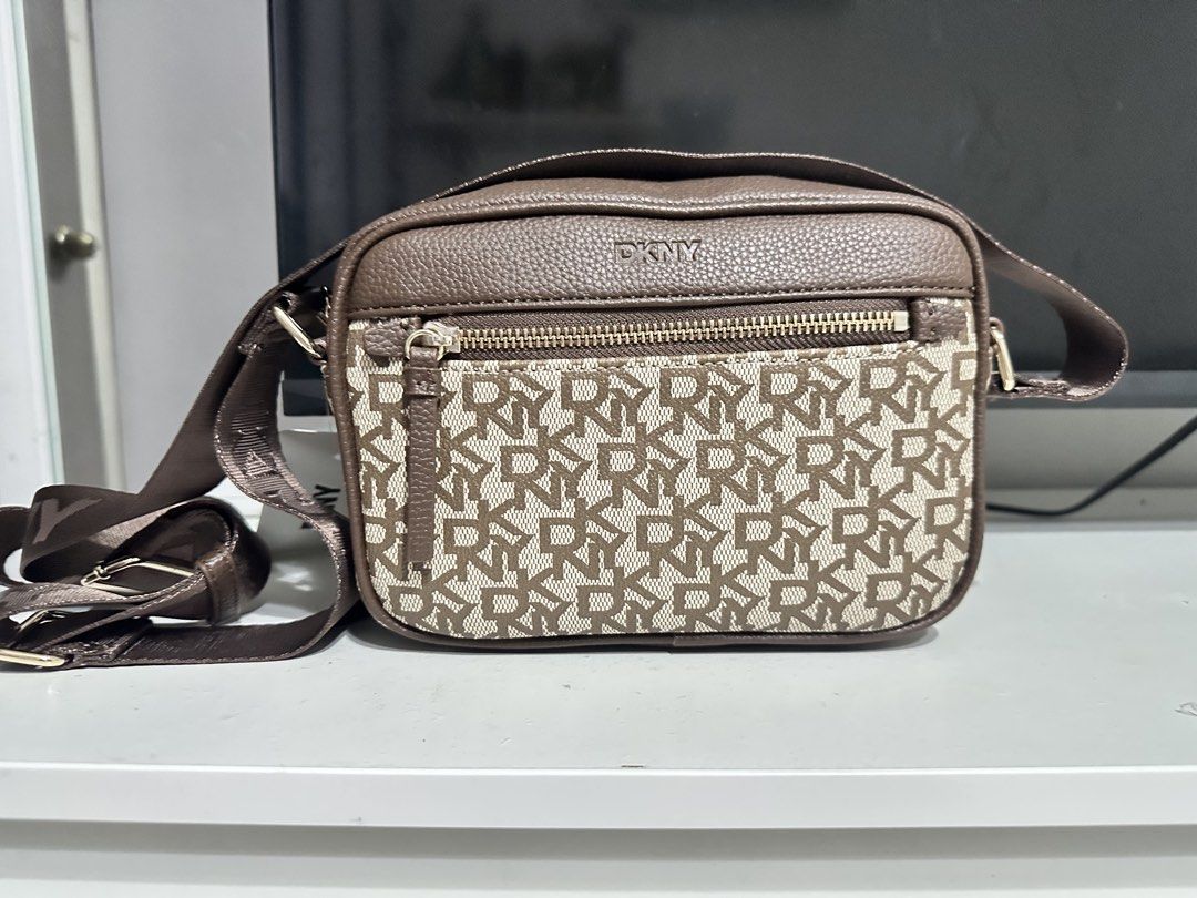DKNY Chocolate Monogram Crossbody Bag (Category: Cross-body Bags) located in San Fernando. Submitted by nyl001 (Listing ID 1454722549, Image 1). Description: - Original brown DKNY crossbody bag - Features all-over DKNY monogram pattern - Main zippered compartment - Front zippered pocket - Adjustable strap for comfortable wear - Comes with original tag.