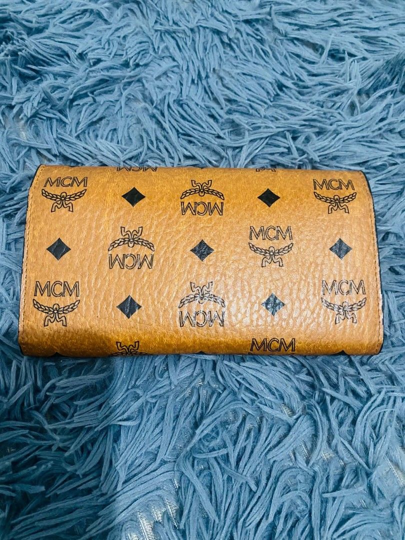 MCM Wallet on chain (Category: Luxury Bags & Wallets) located in Manila. Submitted by keendog_d33509 (Listing ID 1454681745, Image 2). Description: - Classic MCM wallet on chain - Signature Visetos print in warm cognac color - Multiple card slots for organization - Zippered coin pocket - Secure gold hardware closure on the front - Shows some signs of wear. *You can check all details before you confirm. *NO RETURN, NO REFUND ONCE TRANSACTION IS CO