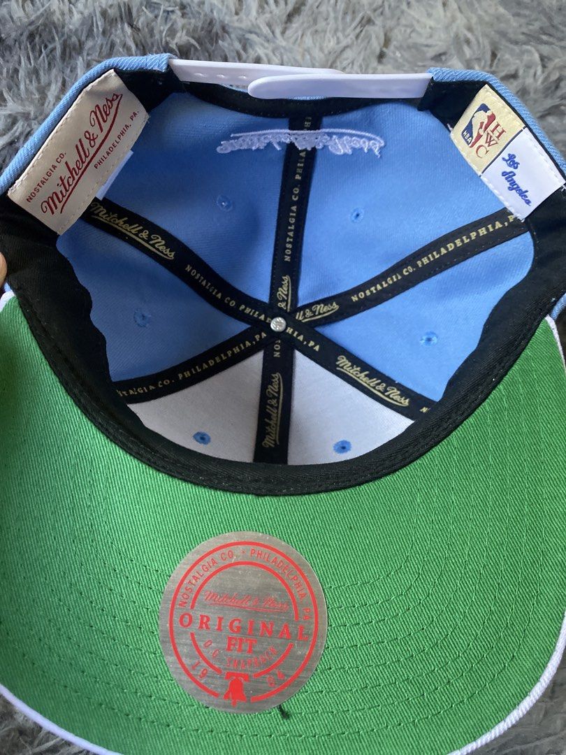 Mitchell & Ness LA Dodgers Snapback Cap (Category: Caps & Hats) located in Manila. Submitted by genesismak85421 (Listing ID 1454645314, Image 2). Description: - Light blue Mitchell & Ness snapback - Features iconic LA Dodgers logo on the front - 'Los Angeles' embroidered on the brim - Classic white snap closure at the back - Mitchell & Ness branding visible on the back and inside - Stylish green underbrim.