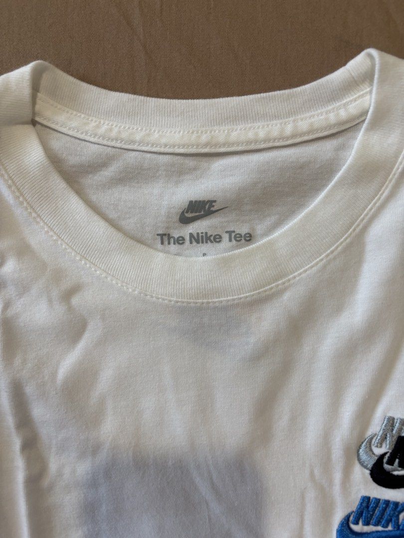 Nike White T-Shirt with Multiple Logos (Category: Tshirts & Polo Shirts ) located in Quezon City. Submitted by aaron.declutters (Listing ID 1454726625, Image 2). Description: - Classic white Nike t-shirt - Features multiple Nike logos on front and back - Main chest logo with blue and black accents - Small red Nike logo on bottom left front - Back features a small embroidered logo with yellow and blue details - Short sleeves and crew neck design -