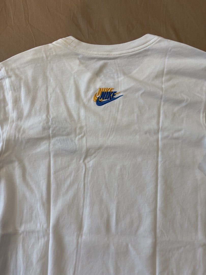 Nike White T-Shirt with Multiple Logos (Category: Tshirts & Polo Shirts ) located in Quezon City. Submitted by aaron.declutters (Listing ID 1454726625, Image 3). Description: - Classic white Nike t-shirt - Features multiple Nike logos on front and back - Main chest logo with blue and black accents - Small red Nike logo on bottom left front - Back features a small embroidered logo with yellow and blue details - Short sleeves and crew neck design -