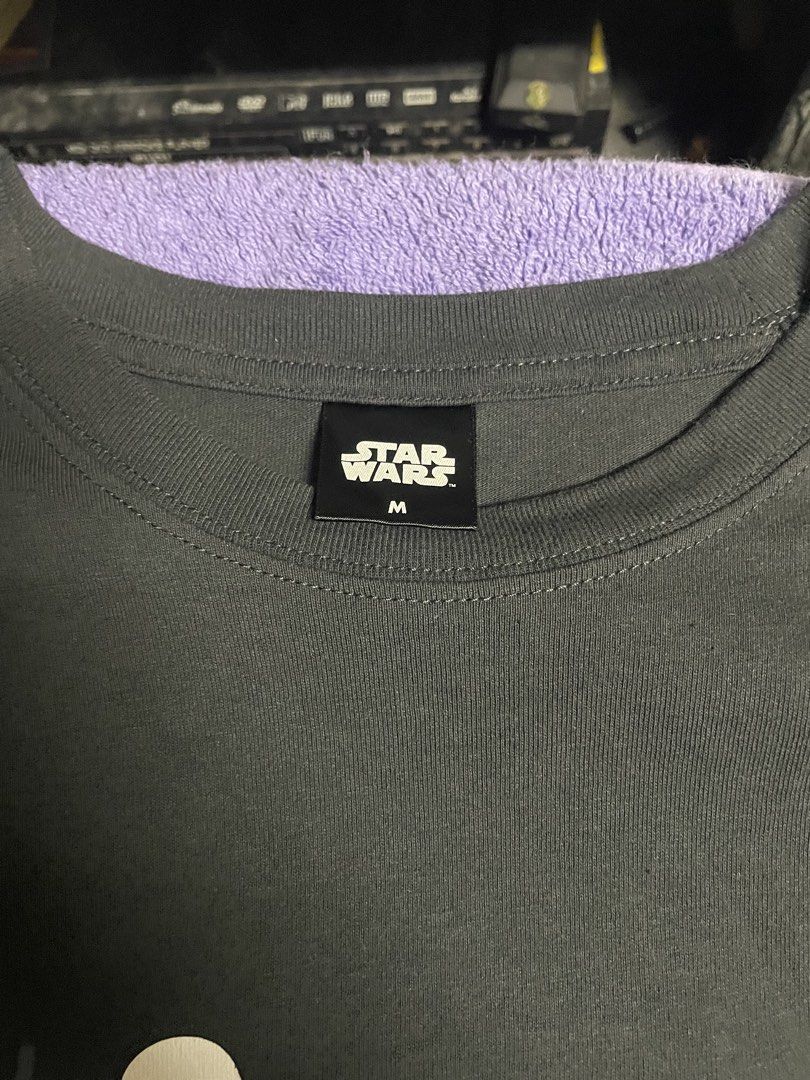 Star Wars Shirt (Category: Activewear) located in Manila. Submitted by 2002kid (Listing ID 1454697409, Image 3). Description: This charcoal grey Star Wars graphic t-shirt features a minimalist cartoon design of a Stormtrooper, R2-D2, and Darth Vader. Design: The shirt showcases a specific cartoon character arrangement with the text “Bloop! Bleep!” above R2-D2.Color: The fabric is a dark charcoal or “ink black” color.Material: It is constructed fr