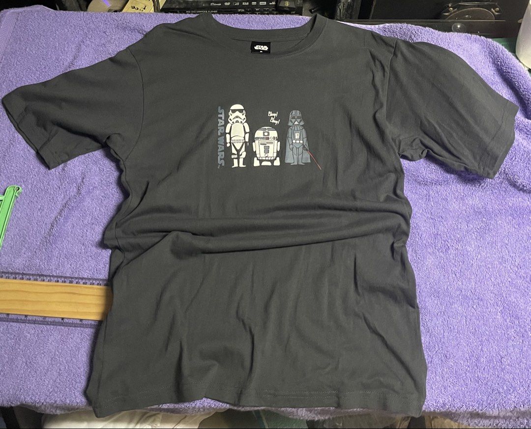 Star Wars Shirt (Category: Activewear) located in Manila. Submitted by 2002kid (Listing ID 1454697409, Image 1). Description: This charcoal grey Star Wars graphic t-shirt features a minimalist cartoon design of a Stormtrooper, R2-D2, and Darth Vader. Design: The shirt showcases a specific cartoon character arrangement with the text “Bloop! Bleep!” above R2-D2.Color: The fabric is a dark charcoal or “ink black” color.Material: It is constructed fr