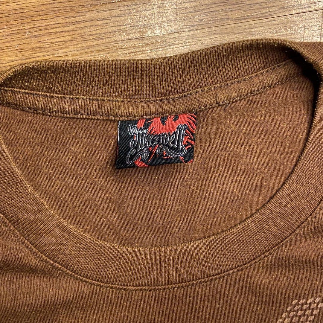 👕 MAXWELL Brown Y2K Graphic Tee (Category: Tshirts & Polo Shirts ) located in Manaoag. Submitted by friends_7 (Listing ID 1459038713, Image 3). Description: Rock that earth-tone 2000s aesthetic with this Maxwell graphic tee! Features a rich heathered brown fabric, chest graphic print with gold foil-like accents, and side hem branding. Great for casual daily fits, street style, or layering. Grab this steal for only ₱189 + sf! Details: • Brand: Ma