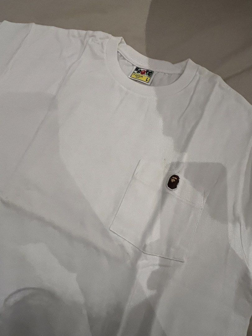 BAPE White Pocket Tee in L (Category: Tshirts & Polo Shirts ) located in Quezon City. Submitted by shopsecondfits (Listing ID 1459034729, Image 1). Description: Has yellow stains due to storage - Brand: A Bathing Ape (BAPE) - Item: White Pocket Tee - Features: Iconic ape head logo on pocket - Includes: Original packaging - Slogan: 'Ape Shall Never Kill Ape' - Size: Large (L) - Ideal for: Streetwear fans.