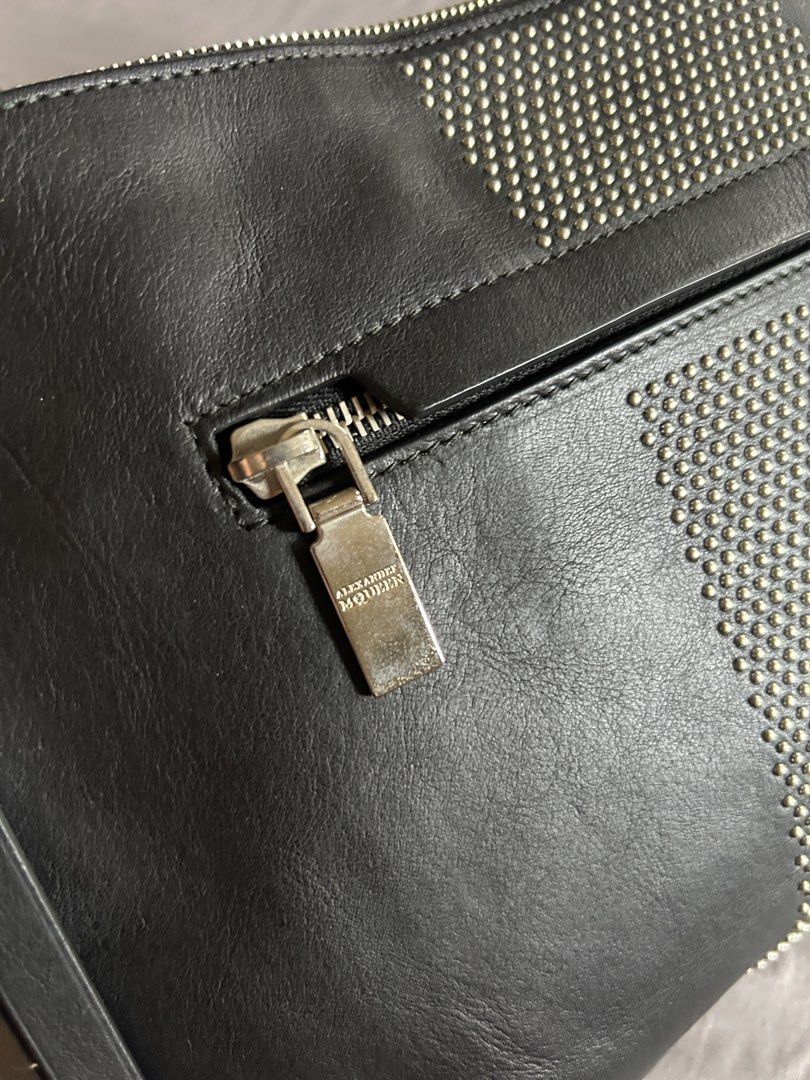 (Authentic) Alexander McQueen Black Leather Studded Clutch (Category: Luxury Bags & Wallets) located in Carigara. Submitted by abiealberca (Listing ID 1458934601, Image 3). Description: - Authentic Alexander McQueen clutch - Genuine black leather (Calf Skin) - Striking silver stud detailing in a striped pattern - Secure skull zipper closure with branded pull tab - Interior label confirms 'Made in Italy' and date code - Comes with original dust ba