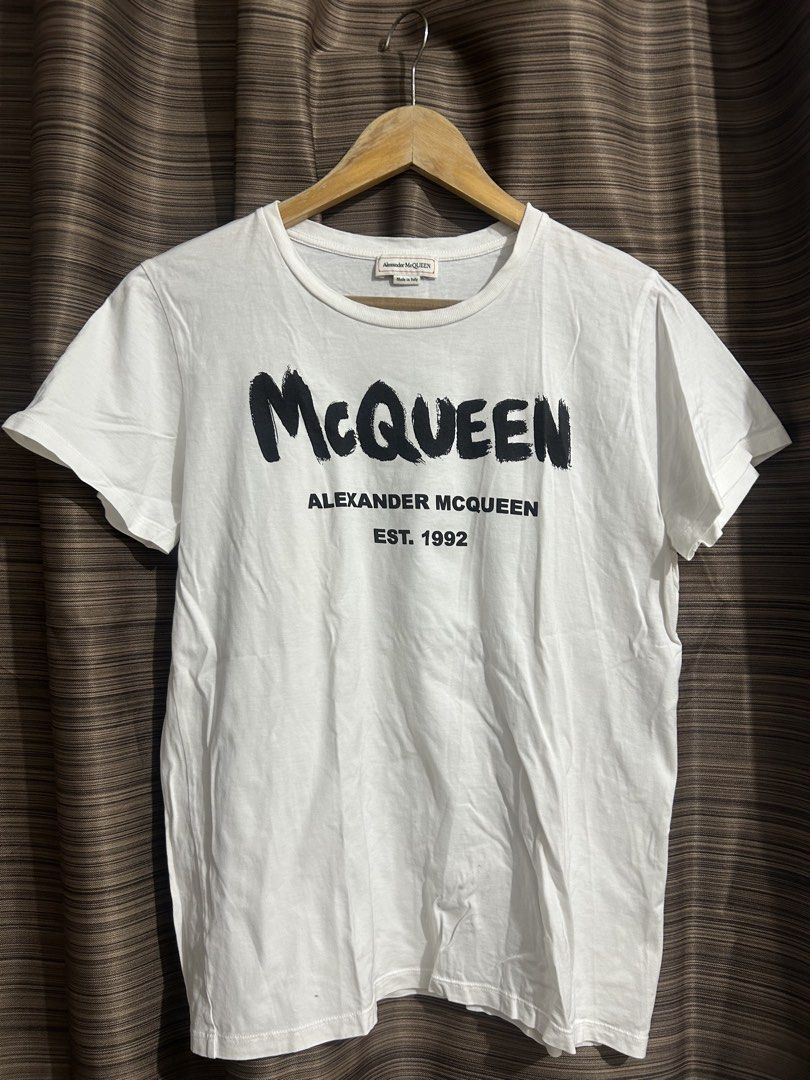 Alexander McQueen White Graphic T-Shirt (Category: Luxury Apparel) located in Tacloban City. Submitted by houseofluxury.co (Listing ID 1458931741, Image 1). Description: - Authentic Alexander McQueen white t-shirt - Features iconic 'McQueen' graphic print - Includes 'Alexander McQueen Est. 1992' text - Made in Italy - Crafted from comfortable cotton material - Ideal for everyday casual wear.