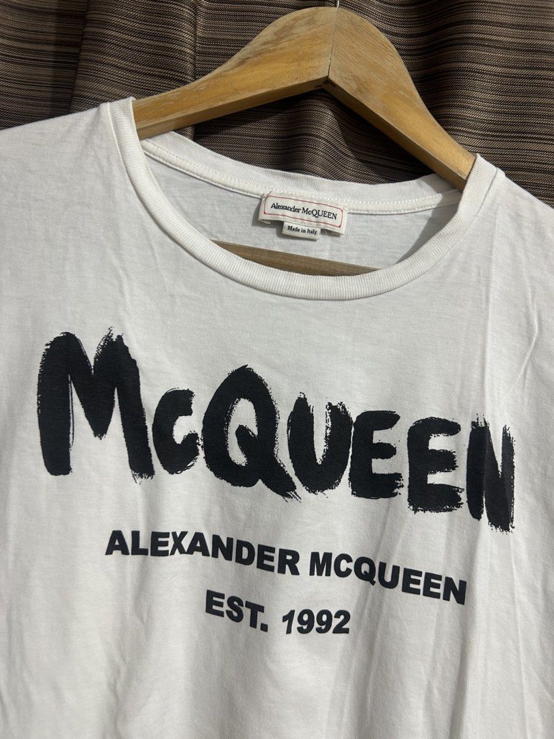 Alexander McQueen White Graphic T-Shirt (Category: Luxury Apparel) located in Tacloban City. Submitted by houseofluxury.co (Listing ID 1458931741, Image 2). Description: - Authentic Alexander McQueen white t-shirt - Features iconic 'McQueen' graphic print - Includes 'Alexander McQueen Est. 1992' text - Made in Italy - Crafted from comfortable cotton material - Ideal for everyday casual wear.