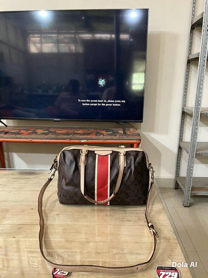 Coach Monogram Speedy Bag with Red Stripe (Category: Luxury Bags & Wallets) located in Buenavista. Submitted by ivoperez27 (Listing ID 1459004126, Image 1). Description: - Authentic brown Coach monogram speedy bag - Eye-catching red and white stripe detail on the front - Classic beige leather trim and handles - Vibrant red interior lining - Secure zipper closure - Comes with a detachable long strap for versatile wear - Minor signs of wear on the 