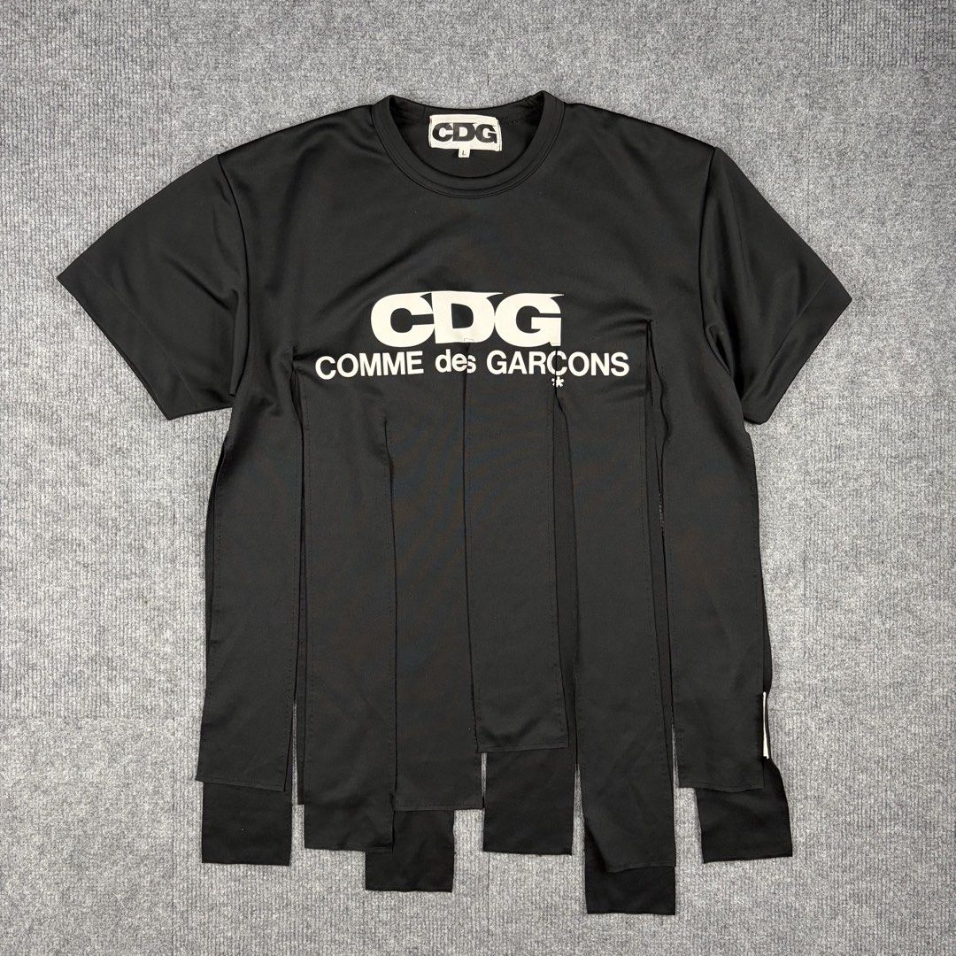 Comme des Garcons Logo Slit Tshirt (Category: Luxury Apparel) located in Manila. Submitted by yourtherapist_ (Listing ID 1459083882, Image 1). Description: Comme des Garcons Logo Slit Tshirt Size: L Condition: 9.5/10 Material: 100% Polyester Made in: Japan Measurements Width: 21.5 Length: 27 Shoulder: 18.5 The hem features numerous slits, creating a fringed design. The front is adorned with a printed “CDG COMME des GARCONS” logo. 5,000.