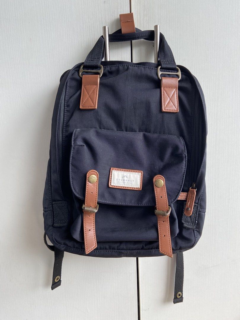 Doughnut Black Backpack with Brown Leather Accents (Category: Backpacks) located in Mandaluyong City. Submitted by coolmami (Listing ID 1458977237, Image 1). Description: - Brand: Doughnut - Color: Black - Accents: Brown faux leather straps and buckle details - Main Compartment: Wide opening for easy access - Interior Organization: Multiple pockets and mesh compartments - Straps: Adjustable shoulder straps - Carrying Options: Top handle - Ideal F