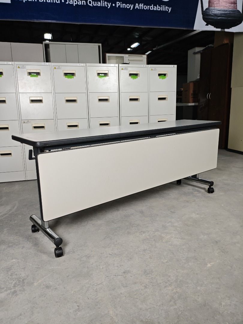 Folding Table with Wheels (Category: Office Furniture & Fixtures) located in Quezon City. Submitted by kevinmacabata12997160 (Listing ID 1458968656, Image 2). Description: White folding conference table with a light grey top. Features a metal frame and wheels for easy transport. Folds for convenient storage..