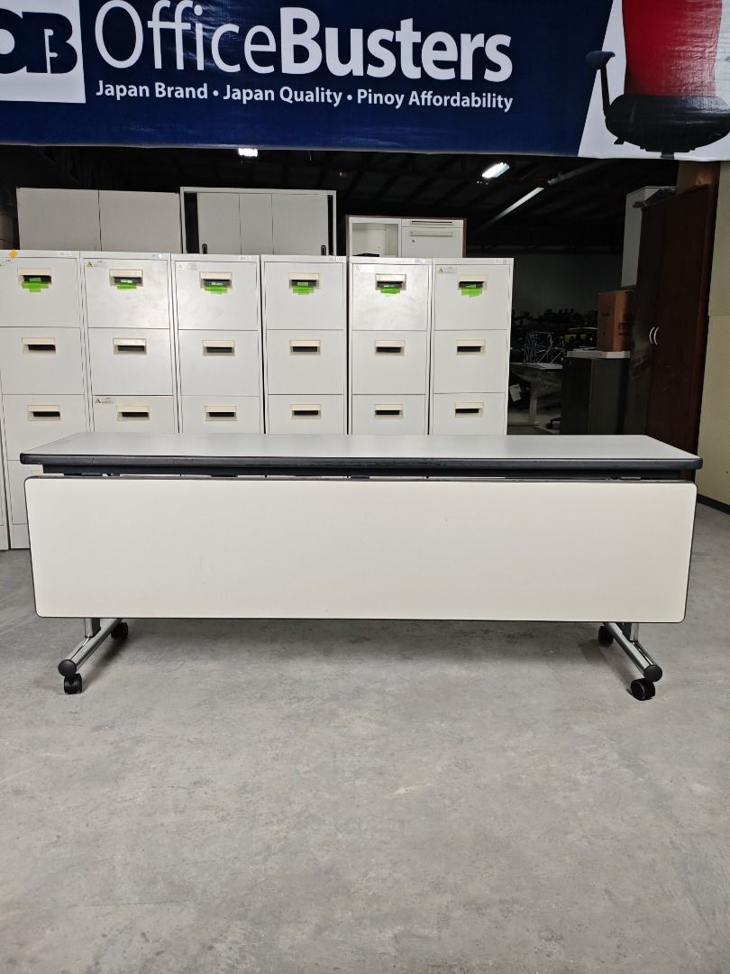 Folding Table with Wheels (Category: Office Furniture & Fixtures) located in Quezon City. Submitted by kevinmacabata12997160 (Listing ID 1458968656, Image 3). Description: White folding conference table with a light grey top. Features a metal frame and wheels for easy transport. Folds for convenient storage..