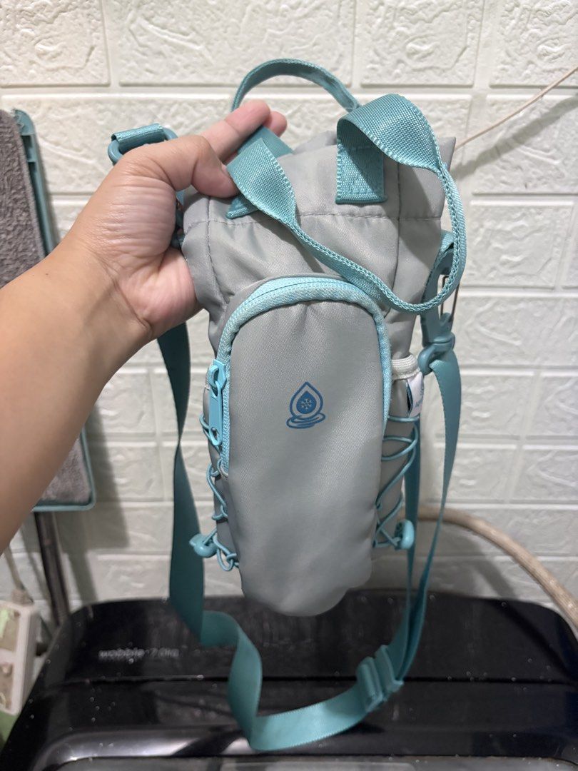 Aquaflasks Water Bottle Bag (Category: Cross-body Bags) located in Manila. Submitted by happytiger-d966 (Listing ID 1458959852, Image 1). Description: *USED TWICE - Stylish grey water bottle bag with vibrant teal straps and zipper. - Convenient small front pocket with a cute water droplet logo. - Adjustable straps ensure a comfortable fit for everyone. - Ideal for hiking, sports, or your daily commute. - Made with easy-to-clean material for hassl