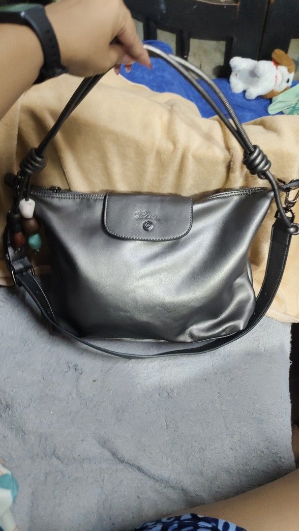 Longchamp "Le Pliage" Shoulder Bag - Metallic Grey (Category: Luxury Bags & Wallets) located in Antipolo. Submitted by robannrave98496 (Listing ID 1458927962, Image 1). Description: - Brand: Longchamp - Model: Le Pliage - Color: Metallic Grey - Closure: Snap and zip top - Features: Detachable strap, cute beaded charms on the side - Style: Shoulder bag - Condition: Great for everyday use - Interior: Plenty of space.