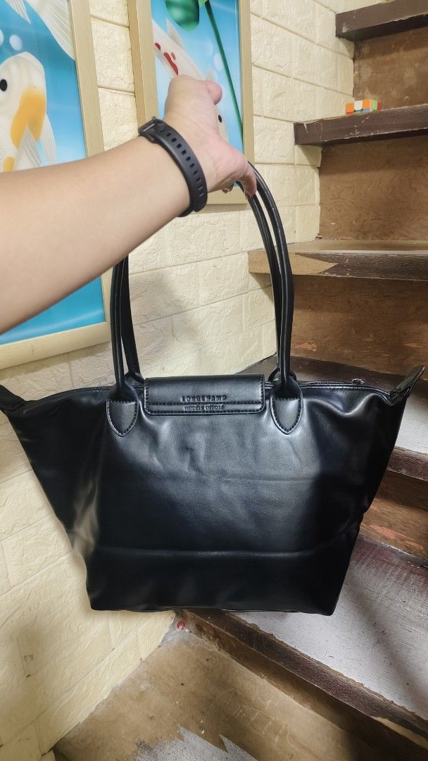 Longchamp Le Pliage Tote Bag Black Leather (Category: Luxury Bags & Wallets) located in Antipolo. Submitted by robannrave98496 (Listing ID 1458955115, Image 2). Description: - Classic black Longchamp tote bag - Made of leather - Signature Longchamp logo on snap closure - Interior features iconic Longchamp pattern - Secure top zipper closure - Comfortable, easy-to-carry handles - Ideal for everyday use.
