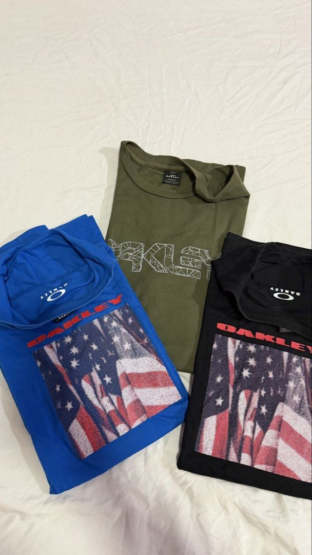 Oakley T-Shirts (3 pcs) - Blue, Black, Olive (Category: Tshirts & Polo Shirts ) located in Naic. Submitted by joancust (Listing ID 1458947767, Image 2). Description: - Brand new Oakley t-shirts - Available colors: Blue, Black, Olive Green - Blue & Black shirts feature an American flag graphic print - Olive Green shirt features a large Oakley logo graphic - Ideal for casual wear - Comfortable and stylish.
