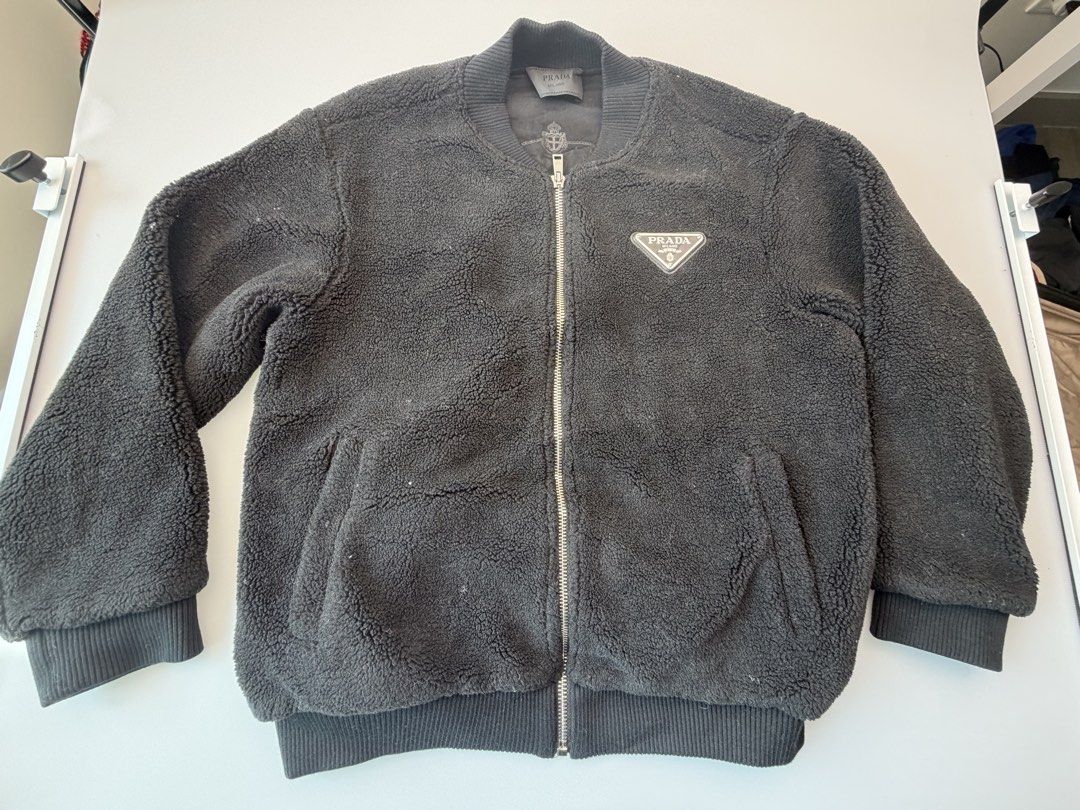 PRADA Fleece Teddy Bomber Jacket (Size M) – Black Enamel Triangle Logo (Category: Luxury Apparel) located in San Juan City. Submitted by vc828 (Listing ID 1458905580, Image 1). Description: PRADA Re-Nylon Fleece Teddy Bomber Jacket (Size M) – Black Enamel Triangle Logo Prada heavyweight sherpa fleece zip bomber jacket in black. Features the iconic Saffiano leather and metal enamel triangle logo on the chest, a large knitted Prada Milano crest mot