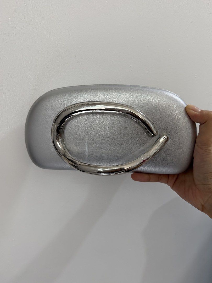 Silver Clutch Bag with Chrome Handle (Category: Clutches) located in Pasig City. Submitted by miss_abuelita (Listing ID 1458953789, Image 2). Description: - Chic silver clutch bag - Features a shiny chrome handle - Unique oval and smooth shape - Ideal for evening events and special occasions - Makes a bold statement - Crafted from faux leather material - Designed for comfortable carrying.