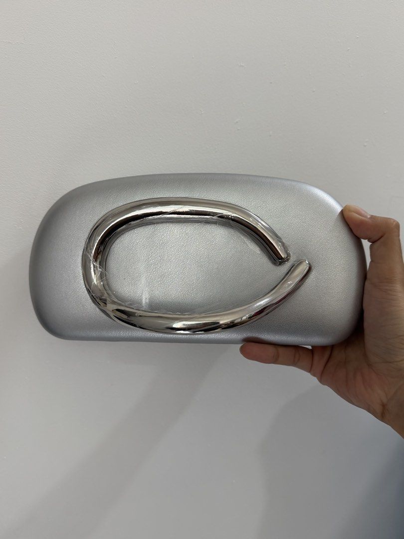 Silver Clutch Bag with Chrome Handle (Category: Clutches) located in Pasig City. Submitted by miss_abuelita (Listing ID 1458953789, Image 1). Description: - Chic silver clutch bag - Features a shiny chrome handle - Unique oval and smooth shape - Ideal for evening events and special occasions - Makes a bold statement - Crafted from faux leather material - Designed for comfortable carrying.