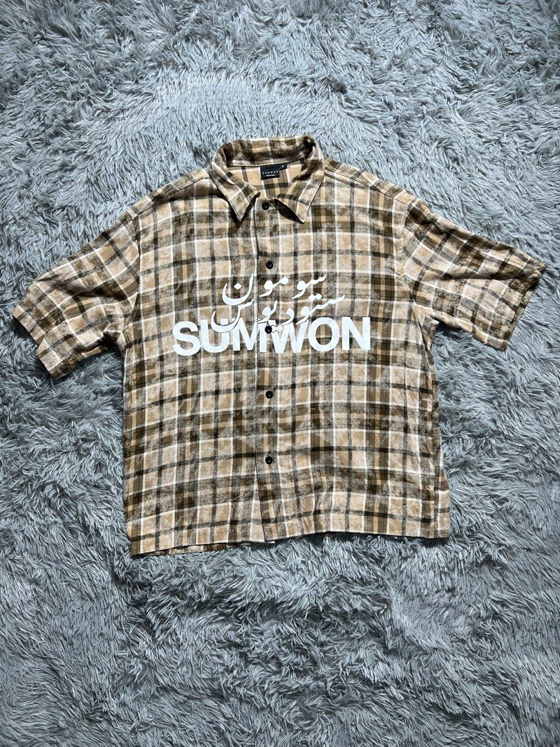 SUMWON Plaid Short Sleeve Button Up Shirt (Category: Tshirts & Polo Shirts ) located in Naga. Submitted by eighttttt (Listing ID 1458918946, Image 1). Description: - Brown and beige plaid short sleeve shirt - Features white Arabic script and 'SUMWON' graphic on the front - Button-up closure - Estimated size S (based on tag) - fit M to L - Ideal for casual wear.