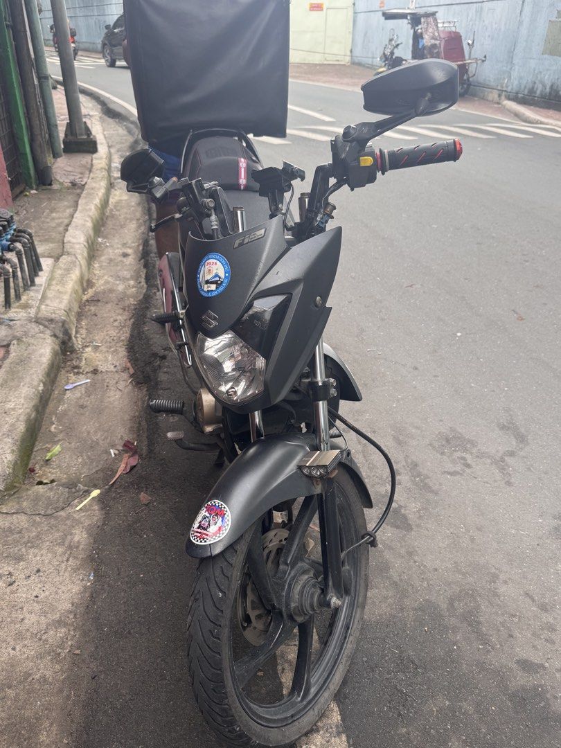 Suzuki Raider J 115 Fi Motorcycle (Category: Motorbikes for Sale) located in Manila. Submitted by sheinevida (Listing ID 1459040255, Image 2). Description: Suzuki Raider J 115 Fi. Matte black finish Jan 2017 model Has a phone mount on the handlebars. Can include used Evo helmets 1 modular and fullface Great for deliveries or daily commute service First owner here❤️ Registered Until FEB 2027 Well maintained sa change oil. Tipid sa Gas consumption.