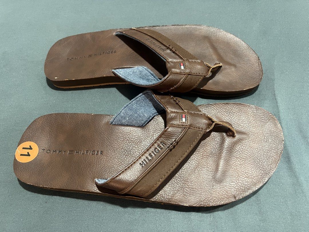 Tommy Hilfiger Brown Leather Flip-Flops Size 11 (Category: Slippers and slides) located in Muntinlupa City. Submitted by cerealrn (Listing ID 1458905673, Image 1). Description: - Brand: Tommy Hilfiger - Color: Brown - Material: Leather straps with denim-like fabric lining - Size: 11 - Sole: Good grip pattern - Style: Casual wear.