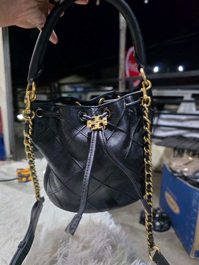 Tory Burch Soft Fleming Black Leather Bucket Bag (Category: Cross-body Bags) located in Lemery. Submitted by venus23 (Listing ID 1458990972, Image 3). Description: - Elegant black leather bucket bag - Stylish quilted pattern - Luxurious gold chain strap - Convenient top handle - Secure drawstring closure - Signature Tory Burch logo hardware - Interior includes a green box - Compact size: approximately 6 inches wide.