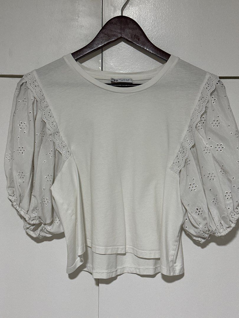 Zara White Eyelet Puff Sleeve Top Size S (Category: Blouses) located in Pasig City. Submitted by tinqsalazar (Listing ID 1458925541, Image 1). Description: - White Zara top - Puff sleeves with eyelet embroidery detail - Short sleeves with elasticated cuffs - Crew neck - Cropped fit - Versatile for casual or dressed-up occasions.