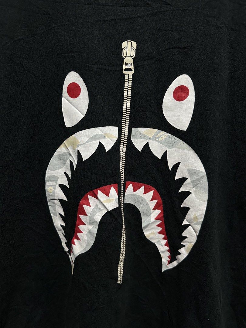 A Bathing Ape (BAPE) Full Zip Shark Tee (Category: Tshirts & Polo Shirts ) located in Buenavista. Submitted by themodernrack (Listing ID 1460901190, Image 2). Description: Brand: A Bathing Ape (BAPE) / NOWHERE Co., Ltd. Tag Size: XL Measurements: 22” Pit-to-Pit x 28” Length Stitching: Single stitch sleeves & hem Color: Faded Black Condition & Details: Pre-owned vintage condition with natural character and wash wear. Features the classic printed S