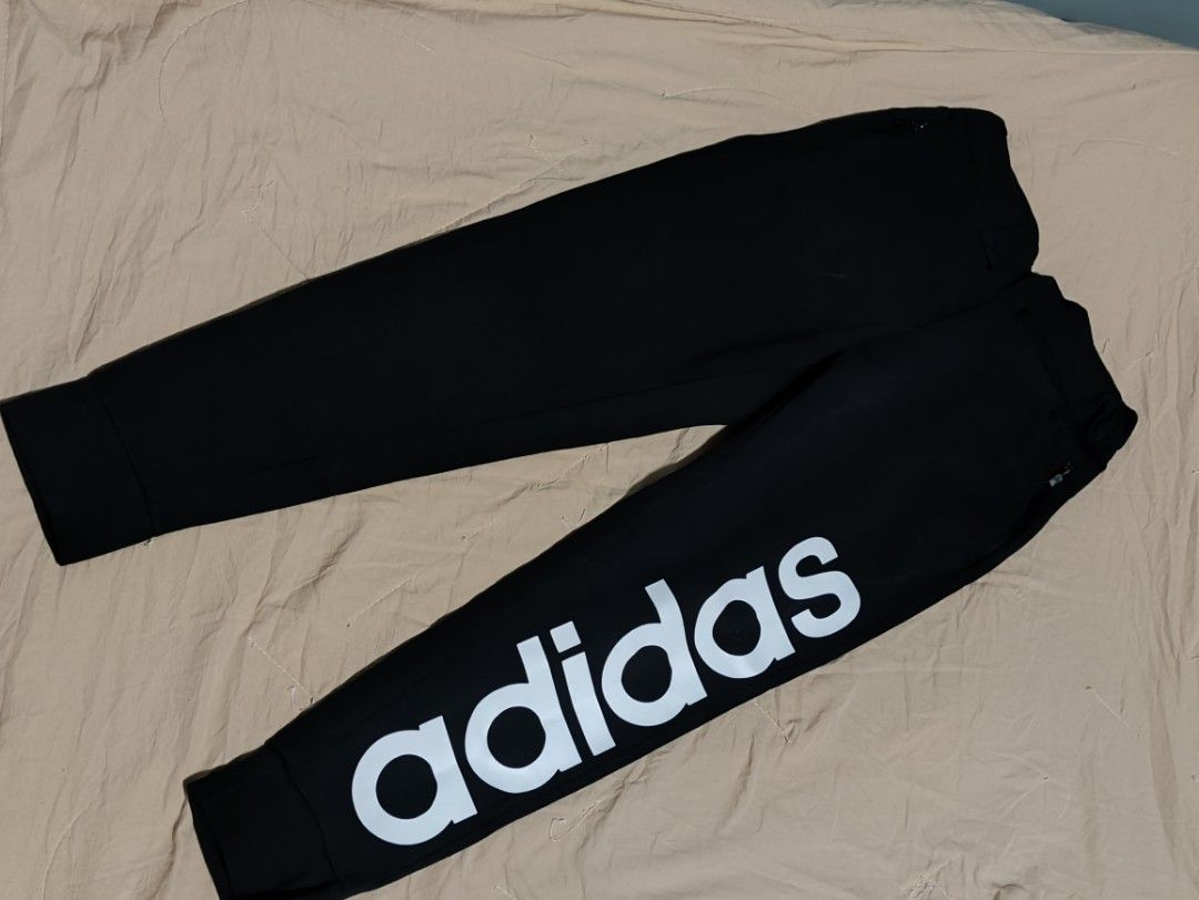 Adidas Black Joggers with Large Logo (Category: Joggers) located in Lucena. Submitted by cha_riz010726 (Listing ID 1460899897, Image 1). Description: - Classic black Adidas joggers - White Adidas logo on the side leg - Elastic waistband with adjustable drawstring - Cuffed ankles for a snug fit - Versatile for casual wear or athletic activities.