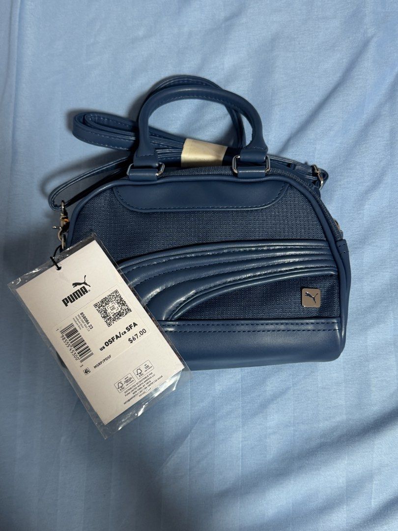 AUTHENTIC Puma Mini Duffle Bag Navy Blue (Category: Cross-body Bags) located in Manila. Submitted by blueishbaddie (Listing ID 1460739339, Image 1). Description: AUTHENTIC Navy blue Puma mini duffle bag - bought in Canada - orig price: $75 CAD w tax / ₱3,394.51 - Features top handles and a detachable shoulder strap - Material is a blend of faux leather and textured fabric - Comes with original tags still attached - Ideal size for carrying your da