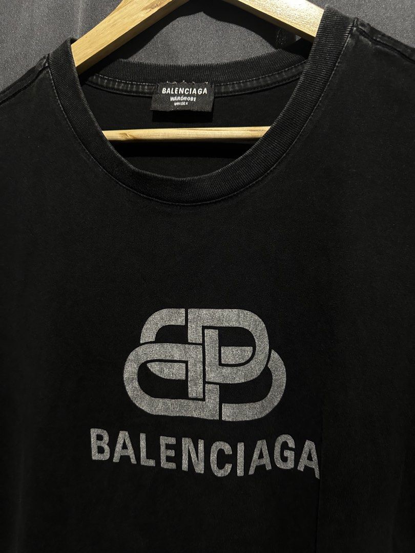 Balenciaga BB Interlocking Logo T-Shirt (Category: Tshirts & Polo Shirts ) located in Buenavista. Submitted by themodernrack (Listing ID 1460800458, Image 2). Description: Brand: Balenciaga Color: Black Style: High-End Streetwear Graphic Tee (Features distress-printed interlocking BB logo and Balenciaga logotype across the chest) Tag Size: Unconfirmed (Fits Medium to Large; see measurements) Condition: Used condition (Fabric fading, neck tag stit