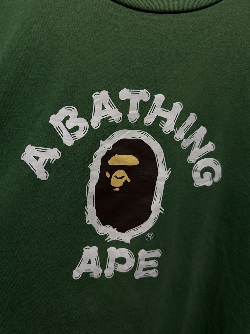 BAPE College Ape Head Graphic Tee (Category: Tshirts & Polo Shirts ) located in Buenavista. Submitted by themodernrack (Listing ID 1460887225, Image 3). Description: Brand: A Bathing Ape (BAPE) Color: Green Style: Short Sleeve Graphic Tee (Classic College Ape Head arch logo front print with back neck “Bape” arch graphic) Tag Size: 3XL (Fits approx. 24” x 29”, see measurements) Condition: Good used condition (Repaired small pinhole, minimal light 