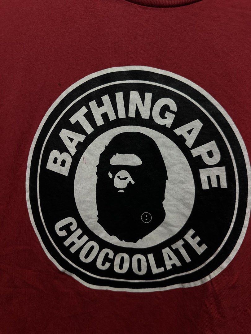BAPE x Chocoolate Circle Seal Ape Head Tee (Category: Tshirts & Polo Shirts ) located in Buenavista. Submitted by themodernrack (Listing ID 1460893845, Image 2). Description: Brand: A Bathing Ape (BAPE) x Chocoolate Color: Red Style: Short Sleeve Graphic Tee (Features circular “Bathing Ape Chocoolate” seal logo print on front) Tag Size: XL (Fits approx. 21” x 29”, see measurements) Condition: Fair used condition (Needs washing; features faint sur
