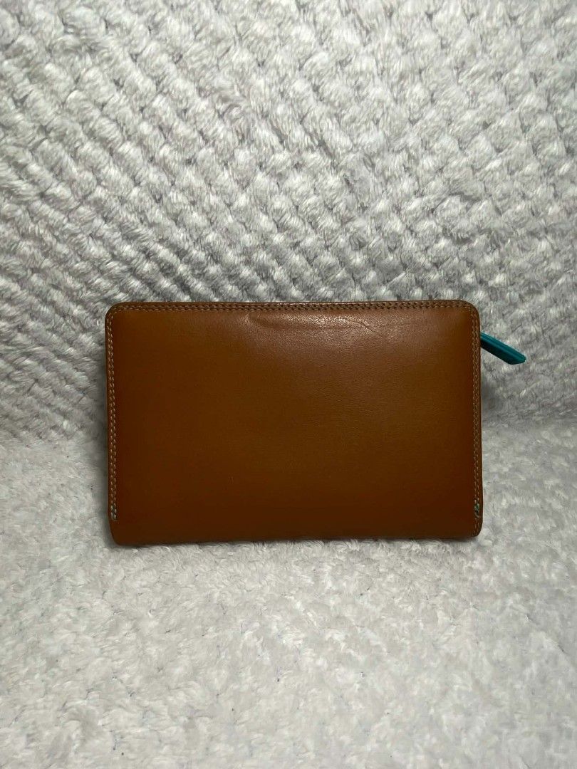 Bifold Leather Wallet (Category: Wallets & Card holders) located in Baguio. Submitted by leah_rodrigo (Listing ID 1460758763, Image 2). Description: - Genuine brown and tan leather bifold wallet - Multiple card slots and compartments for superior organization - Unique small turquoise accent on the zipper pull - Perfect for keeping your essentials tidy - Approximate dimensions when closed: 7 inches x 4 inches.