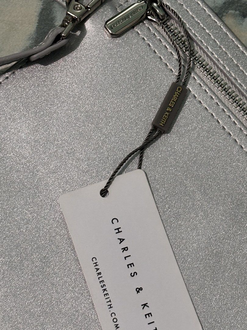 Charles & Keith Silver Metallic Clutch Bag with Tag (Category: Clutches) located in La Trinidad. Submitted by caicai1926 (Listing ID 1460808829, Image 3). Description: - Brand: Charles & Keith - Color: Silver Metallic - Condition: Brand new with original tag attached - Closure: Zip closure - Style: Simple, sleek clutch - Occasion: Ideal for evenings out or adding a touch of shine to your look.