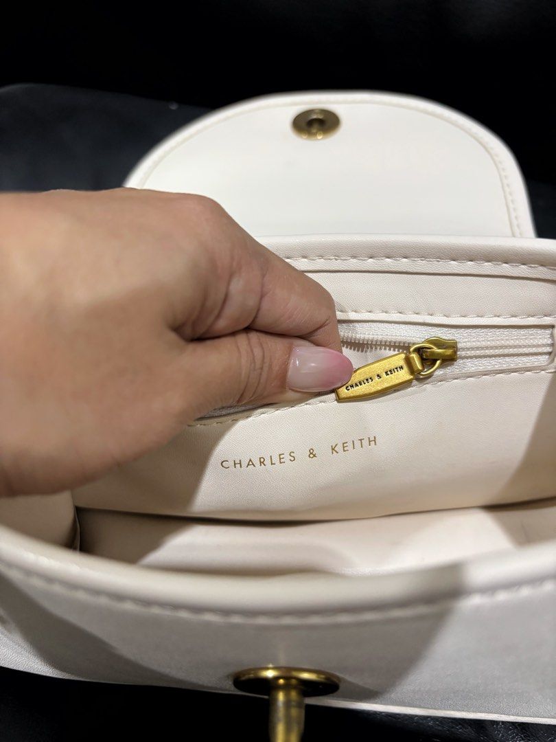 Charles & Keith White Handbag with Gold Hardware (Category: Luxury Bags & Wallets) located in Digos. Submitted by kathydiane76376 (Listing ID 1460741369, Image 3). Description: - Brand: Charles & Keith - Color: White - Hardware: Gold details (ring on front flap, chain strap) - Interior: Main compartment, inner zip pocket, clean interior - Style: Versatile, suitable for everyday or special occasions.