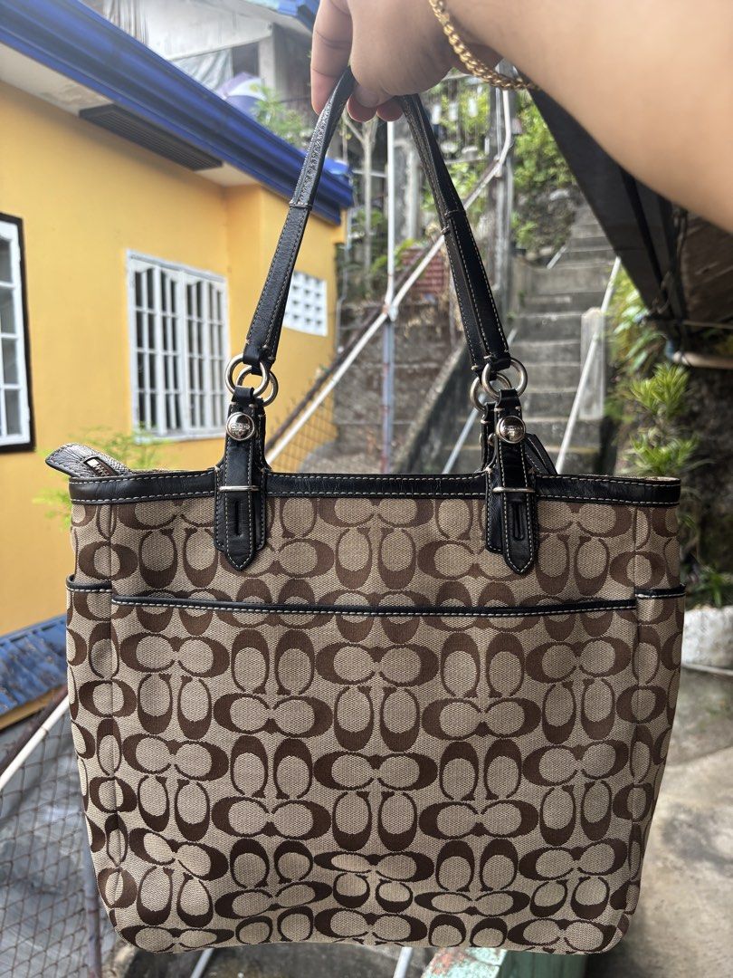 Coach Gallery Signature Tote Bag (Category: Tote Bags) located in Cebu City. Submitted by jhon32closetfinds (Listing ID 1460917082, Image 2). Description: Pattern: Repeating classic "C" signature monogram weave.Hardware: Sturdy silver-tone metal ring connections at the handle base and a central "COACH EST. 1941" metallic logo placard.Details: Distinct pleated accents on the front face and convenient slip pockets situated on both sides.Era: A high