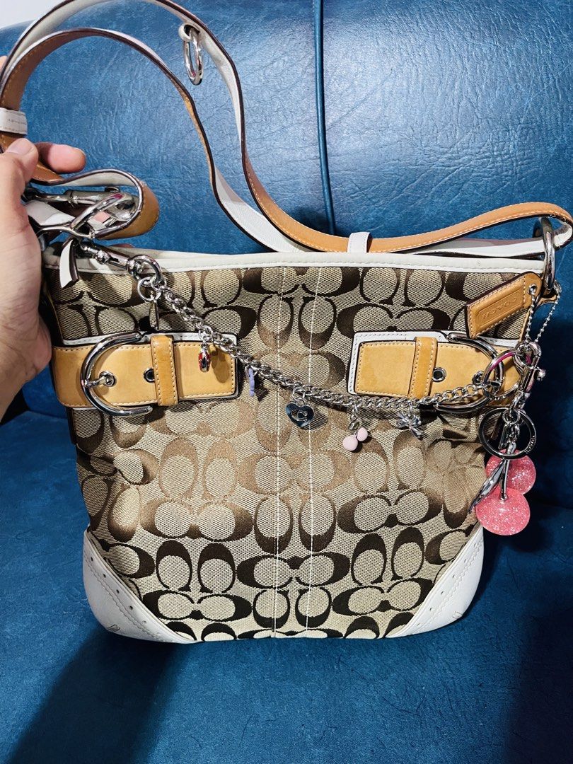 Coach Signature Monogram Canvas & Leather Shoulder Bag (Category: Luxury Bags & Wallets) located in Manila. Submitted by lenilynloy68852 (Listing ID 1460898877, Image 1). Description: - Classic Coach monogram canvas shoulder bag - Tan and brown signature 'C' pattern - White leather trim and tan leather accents - Silver hardware with cute charms - Adjustable shoulder strap - Spacious interior for essentials - Stylish everyday bag.
