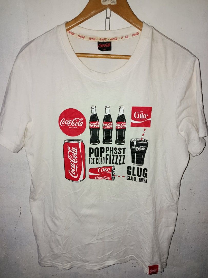 Coca-Cola Graphic T-Shirt (Category: Tshirts & Polo Shirts ) located in Nabunturan. Submitted by marmitoren42236 (Listing ID 1460872159, Image 1). Description: - White Coca-Cola graphic t-shirt - Features iconic Coke bottles, cans, and cups - Text includes 'Pop, Phsst, Ice Cold, Fizzzz, Glug, Ahhhh' - Made from comfortable cotton material - Ideal for casual wear - Perfect for any Coca-Cola fan.
