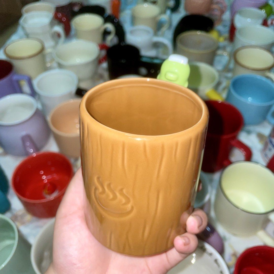 Cute Ceramic Mug with Tree Bark Texture and Green Topper (Category: Coffee & Tea Tableware) located in Valenzuela. Submitted by baekhyunie_pau (Listing ID 1460810306, Image 2). Description: Unique orange-brown mug with tree bark texture and a cute green character topper. Features some writing. Perfect for coffee/tea or display. See other mugs!.