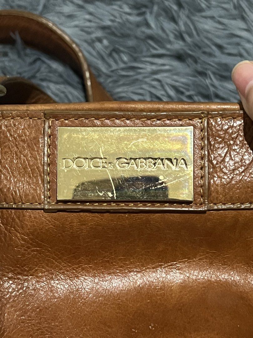 Dolce & Gabbana Brown Leather Tote Bag (Category: Luxury Bags & Wallets) located in Cainta. Submitted by xkengkaix (Listing ID 1460909216, Image 3). Description: - Authentic Dolce & Gabbana brown leather tote bag - Elegant gold hardware and buckle details - Spacious interior with multiple compartments - Shows some signs of wear on the gold plate and leather (adds character!) - Ideal for everyday use, stylish and practical.