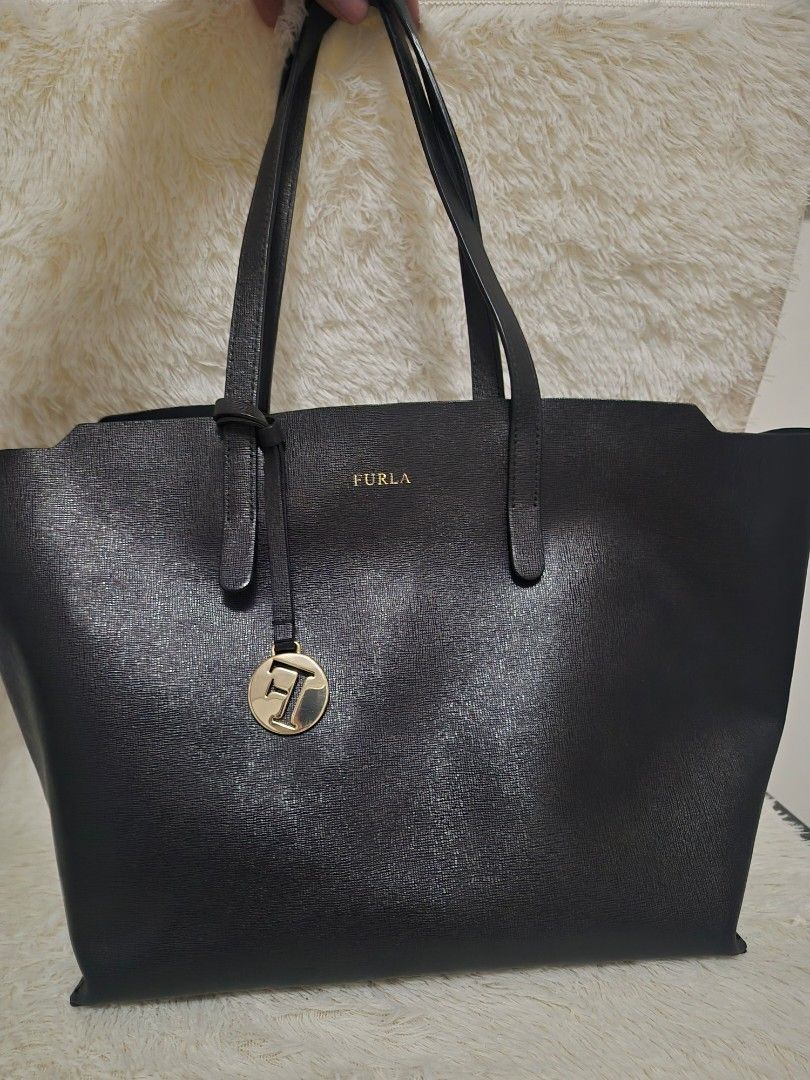 Furla Black Leather Tote Bag - OG (Category: Luxury Bags & Wallets) located in Alaminos. Submitted by tindahanicera (Listing ID 1460772000, Image 2). Description: - Classic black Furla tote bag - Textured leather exterior - Elegant gold hardware (logo charm, zipper pull) - Roomy interior for essentials - Ideal for everyday or travel H - 10.5 in L - 12 in (bottom) 17in (top) W - 6 in Handle - 18 in.