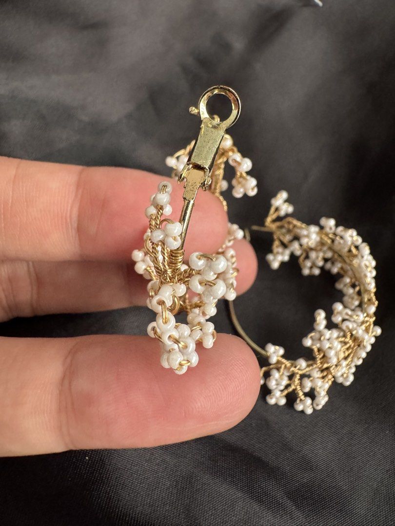 Gold Hoop Earrings with White Beads (Category: Earrings) located in Angeles City. Submitted by thala.1204.68 (Listing ID 1460743741, Image 3). Description: - Chic gold hoop earrings - Adorned with small white beads clustered to resemble flowers or berries - Intricate gold wire detailing - Secure and reliable clasp closure - Versatile accessory: elevates both casual and formal outfits - Adds a touch of flair and elegance to any look.